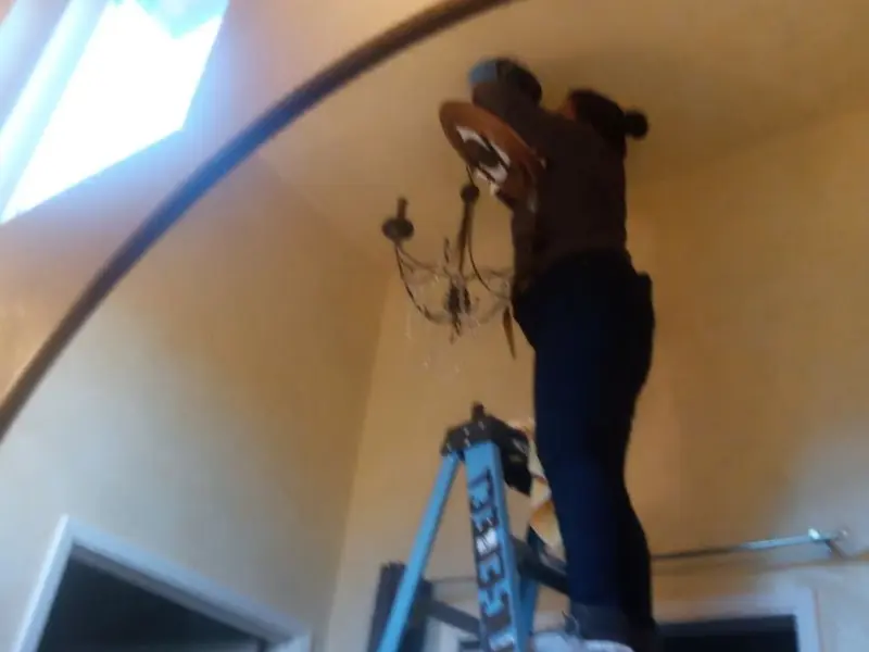 Electrician installing a chandelier in a Townsend residence